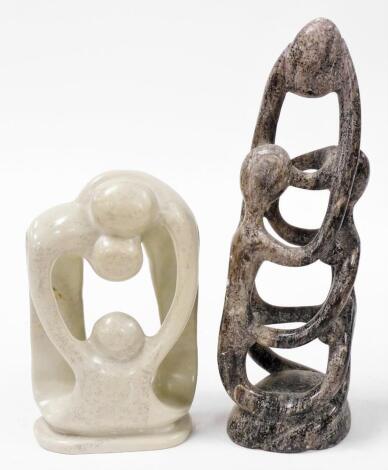 Two soapstone figure groups, one of parents and child in mottled tones, 25cm high, the other, 38cm high.