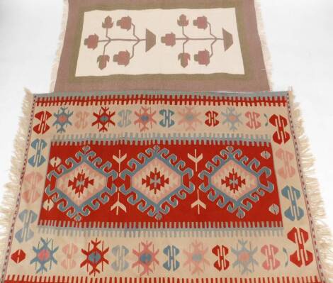 Two rugs, to include a wool rug, of rectangular form with Aztec, red blue, pink and white scarabs, with tassel ends, 173cm x 122cm and another wool cut rug of modern design with central rectangular panel depicting flowers in vase, in cream with brown and 