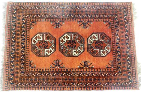 A Persian style wool rug, in orange, cream and black, with the three central motifs and five various borders, 145cm x 100cm, with tassel ends.