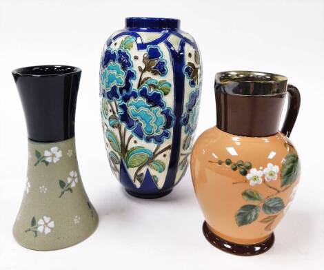 A group of three ceramics, to include a Doulton Lambeth stoneware vase, with blue glazed top and green floral swat base, 20cm high stamped England patent number 8687, partially stamped ceramic jug, with brown stoneware rim and handle, on pink glazed flora