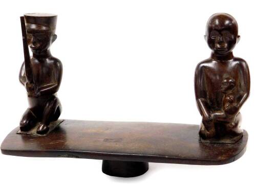 A 20thC African tribal carving, formed as two removable figures on a shaped block base, 46cm wide.