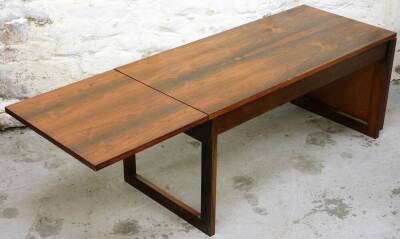 A Danish rosewood coffee table, of rectangular form, drop leaves and plain top on block stiles, (when closed) 46cm high, 104cm wide, 46cm deep.