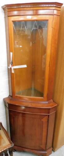 A yew corner cabinet, the moulded cornice above a single astragal glazed door, and cupboard door base, 184cm high, 67cm wide, 48cm deep.