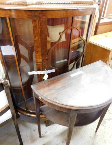 Two items of furniture, to include a 1960s oak curved display cabinet, the glazed front with panelling on ball and claw feet, 124cm high, 93cm wide, 35cm deep, together with a demi-lune side table, with glass top.