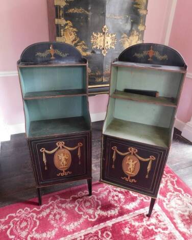 A pair of George III painted waterfall side cabinets, on a black ground, each with a raised top above two shelves, the base with a panelled door, carved with a putto, swags, ribbons, etc., on slender square tapering legs, 127cm high, 48cm wide, 27cm deep.