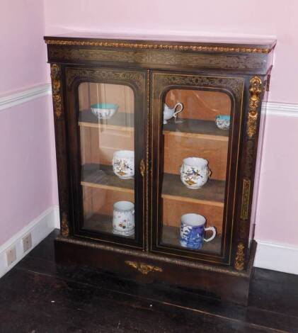 A late 19thC ebonised and brass inlaid side cabinet, with gilt metal mounts, the plain top above a leaf cast frieze, above two glazed doors enclosing a velvet lined interior, on a plinth base, 116cm high, 97cm wide, 32cm deep.