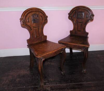 A pair Victorian oak hall chairs, the shield shaped back with carved Pegasus crest, the solid serpentine seat with moulded edge on cabriole legs.