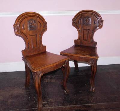 A pair Victorian oak hall chairs, the shield shaped back with carved Pegasus crest, the solid serpentine seat with moulded edge on cabriole legs. - 2