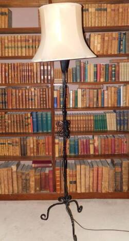 A 20thC wrought iron standard lamp, decorated with scrolls on tripod base, with a cream shade, 192cm high.