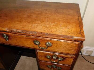 A George III mahogany kneehole desk, the top with a moulded edge above a frieze drawer and flanked by six small drawers, each with cast brass handles around a central panelled door on a plinth base, 74cm high, 96cm wide, 50cm deep. - 3