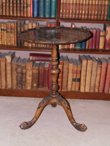 A mahogany occasional table, the circular dished pie crust top, on a turned column and tripod base, carved with leaves and paw feet, in part George III, adapted, 74cm high, 54cm wide.
