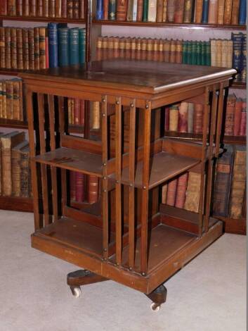 A Edwardian mahogany revolving bookcase, with slatted supports on X shaped base with ceramic castors, stencil mark for the American Patent Revolving Bookcase, manufactured by Trubner and Co Ludgate Hill London, 90cm high, 60cm wide.