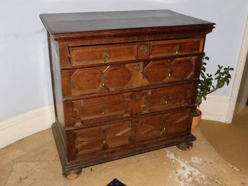 A late 17th/early 18thC oak chest of drawers, the planked top with a moulded edge, above four graduated panelled drawers each with brass pear drop handles, on bun feet, 98cm high, 101cm wide, 58cm deep. (AF)