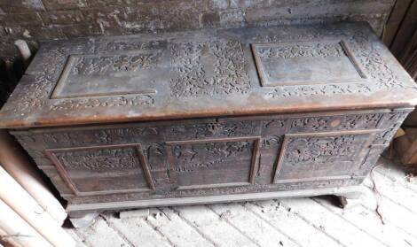 A large 17thC carved poker work walnut coffer, the lid with iron strap hinges and carved figural and lion decoration in blind fret designs, repeated to the front and with paneling and with iron bracket bound corners, on a later plinth base with shallow br