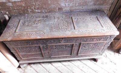 A large 17thC carved poker work walnut coffer, the lid with iron strap hinges and carved figural and lion decoration in blind fret designs, repeated to the front and with paneling and with iron bracket bound corners, on a later plinth base with shallow br - 2