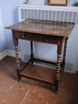 A late 17th/early 18thC oak side table, the rectangular plank top with a moulded edge, frieze drawer with brass drop handles, on bobbin turned supports, 74cm high, the top 65cm wide, 53cm deep.