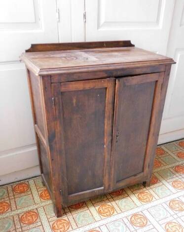 A stained pine and ply side cabinet, with a raised top, two panelled doors enclosing shelves, on end supports, 96cm high, 40cm deep, 76cm wide.