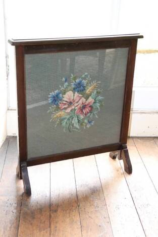 An Edwardian mahogany firescreen, inset with a later tapestry, floral panel on tapering end supports, 63cm wide.