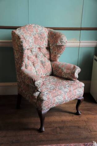 A mahogany wingback armchair in mid 18thC style, upholstered in floral fabric on cabriole legs with pad feet.