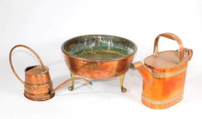 A circular copper planter on three brass feet, 34cm diameter, and two copper watering cans. (3)