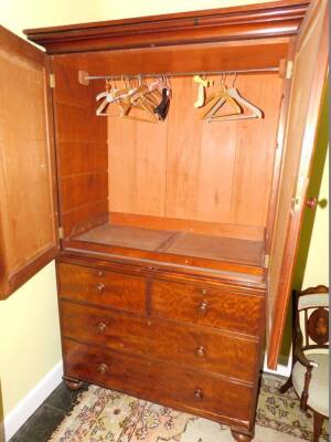 A Victorian mahogany clothes press, the top with a moulded cornice above two arched panelled doors enclosing a later fitted clothes rail, the base with two short and two long drawers, on bun feet, 212cm high, 232cm wide. - 2