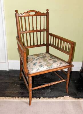 A Edwardian walnut open armchair, with fine spindle turned supports, a padded seat and splayed legs.