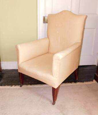 An Edwardian mahogany armchair, upholstered in green calico fabric, on square tapering legs with brass castors.