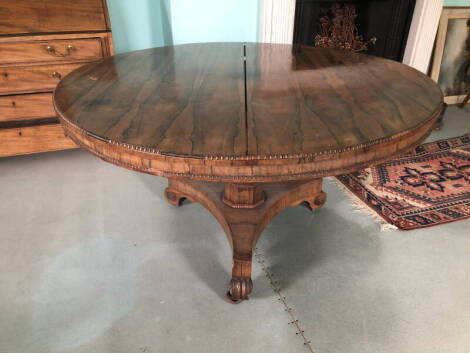 A William IV rosewood breakfast table, the circular top with a beaded border on octagonal tapering column, concave triform base and scroll carved feet, 73cm high, 129cm diameter.