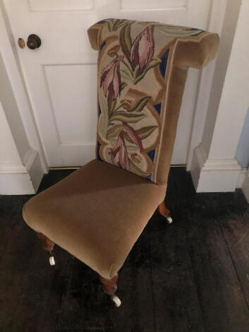 A Victorian walnut prie dieu chair, with a floral wool work back upholstered in brown fabric, on turned tapering legs with ceramic castors.