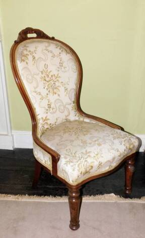 A Victorian walnut show frame spoon back chair, with a moulded frame upholstered in floral fabric on turned tapering legs.
