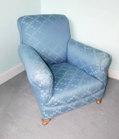 An Edwardian armchair, re-upholstered in patterned fabric, on bun feet with later castors.