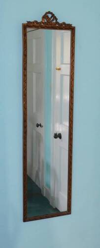 A rectangular gilt wall mirror, the frame decorated with ribbons, etc., 134cm high, 34cm wide.