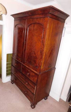 A Victorian mahogany linen press, with moulded cornice, two arch doors revealing press drawers over two short and two long graduated drawers with knop handles and turned feet, 225cm high, 138cm wide.