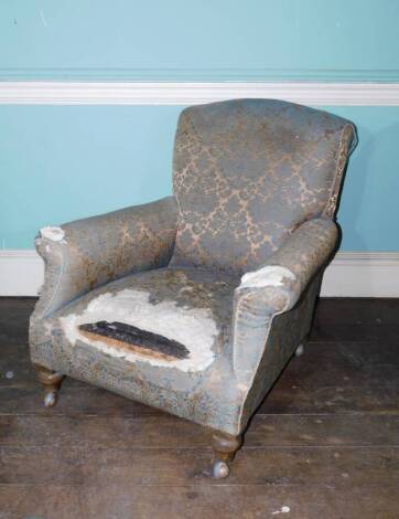 A late 19thC/early 20thC deep armchair, upholstered in gold and blue fabric on beech turned tapering legs and later castors. (AF)