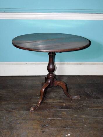 An early 19thC oak occasional table, the circular planked tilt top on a turned column and a tripod base with pad feet, 71cm high, 83cm diameter.