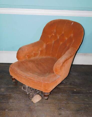 A Victorian walnut low deep seated armchair in the manner of Howard & Sons, upholstered in orange cord, on four turned legs each with ceramic castors. (AF)