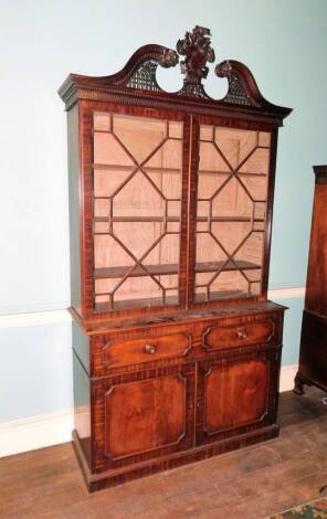 A George III mahogany secretaire bookcase, the associated top with a swan neck pediment central elaborate cartouche carved with an armorial with sword, above a blind fret and dentil frieze and two astragal glazed doors enclosing adjustable shelves, the ba