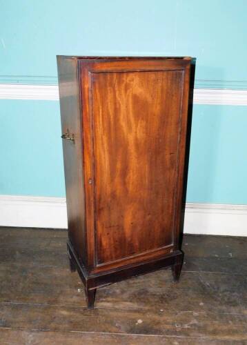 An early 19thC mahogany folio cabinet, the top with a moulded edge above a single panelled door enclosing shelves flanked by brass side handles on square tapering legs, 108cm high, 47cm wide, 34cm deep. (AF)