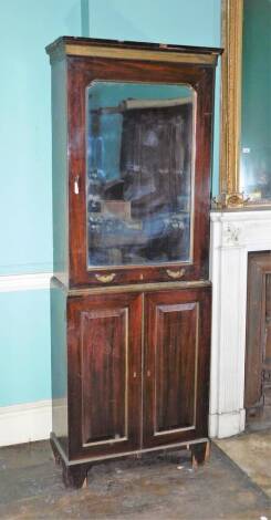 A 19thC mahogany and brass side cabinet, the top with a moulded cornice above a brass frieze and a single mirrored glass door with parcel gilt slip and a pair of brass handles, enclosing a fitted interior with pigeon holes and drawers, the base with two p