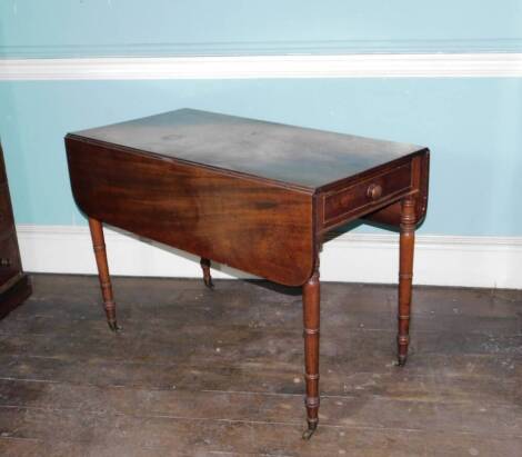 An early Victorian mahogany Pembroke table, the top with rounded corners above a frieze drawer opposing a false drawer with single turned handle, on ring turned tapering legs with brass castors, 72cm high, 108cm wide.