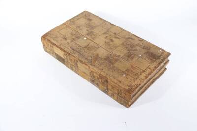 A 19thC back gammon box, with leather lined interior and gilt decoration, the outer hinged case with chequer board and leather bound faux book decoration, and a set of draughts, two shakers and a dice.
