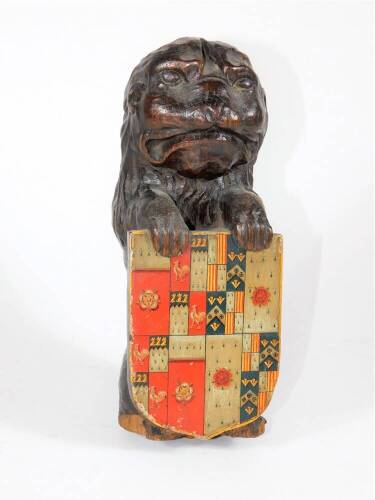 A 19thC carved oak lion surmount, in a seated pose holding an heraldic shield, 25cm high.