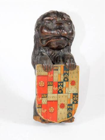 A 19thC carved oak lion surmount, in a seated pose holding an heraldic shield, 25cm high.