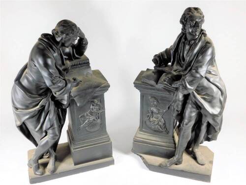 A pair of Victorian black basalt style cast plaster figures, of two scholars in 18thC dress, both depicted leaning on classical square pillars, in a black basalt glaze, 53cm high & 51cm high (AF)