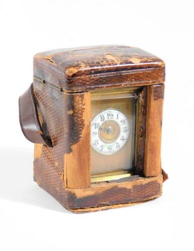 A late Victorian brass cased carriage clock, the enamelled chapter ring with Arabic numerals, visible escapement, 10cm high (handle up), and the red leather travelling case, with key.