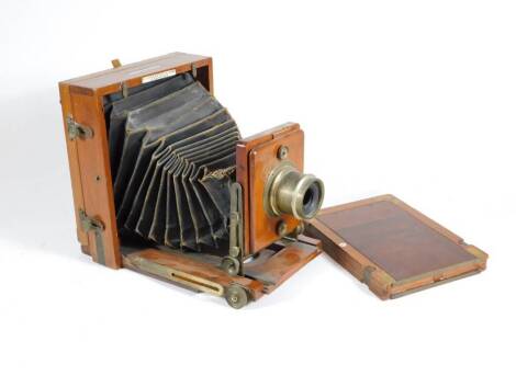 A late Victorian mahogany folding plate camera by J Lancaster and Son Birmingham, having brass furnishings and inset with tablet inscribed 'The 1890 instantphotograph patent', with lens and plate holder.