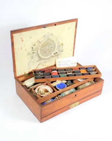 A George III mahogany artist's paint box for R Ackermann of Regent Street, the fitted interior with a tray of watercolour tablets and with porcelain bowls and various paints, glass jars, etc., with a paper label for R Ackermann to the hinged lid, together