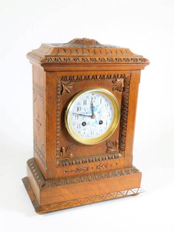 An Edwardian eight day mantel clock, with white enamel and blue painted circular dial, having Arabic numerals and bearing the name of Rowel & Co, Oxford, with French striking eight day movement, stamp mark Marc of Paris and numbered 65858, in a carved oak