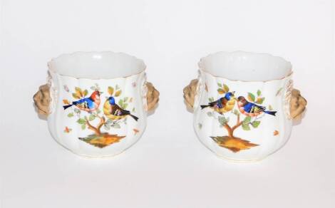 A pair of Dresden porcelain cache pots, hand painted with birds and having lion mask handles, AR scroll mark in underglaze blue, 12cm high. (AF -one with a loss to the rim)