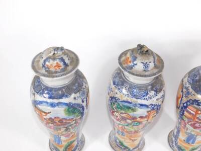 A group of four 18th/19thC Chinese famille rose and blue and white porcelain vases, comprising three baluster vases with covers and a flared beaker vase with similar court scenes and reservoirs in polychrome colours, 18cm high. (AF - various losses and re - 2